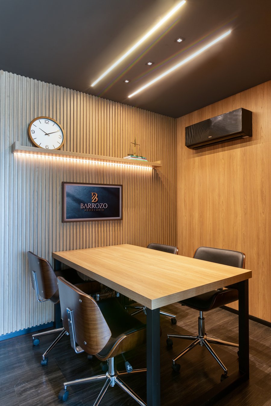 Sala de reunião com mesa de madeira e painel da marca
